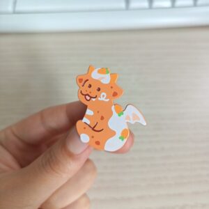dyed orange metal soft enamel pin with silkprint above the metal